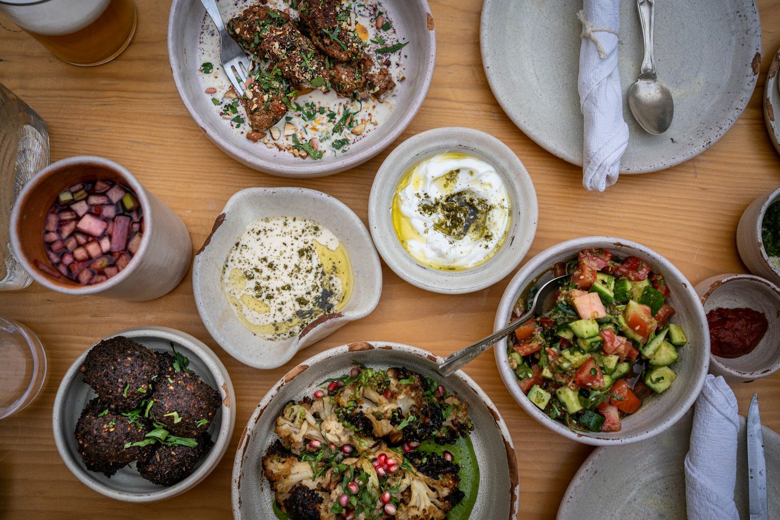 stół zastawiony kilkunastoma miseczkami mezze z hummusem, oliwkami i chlebem
