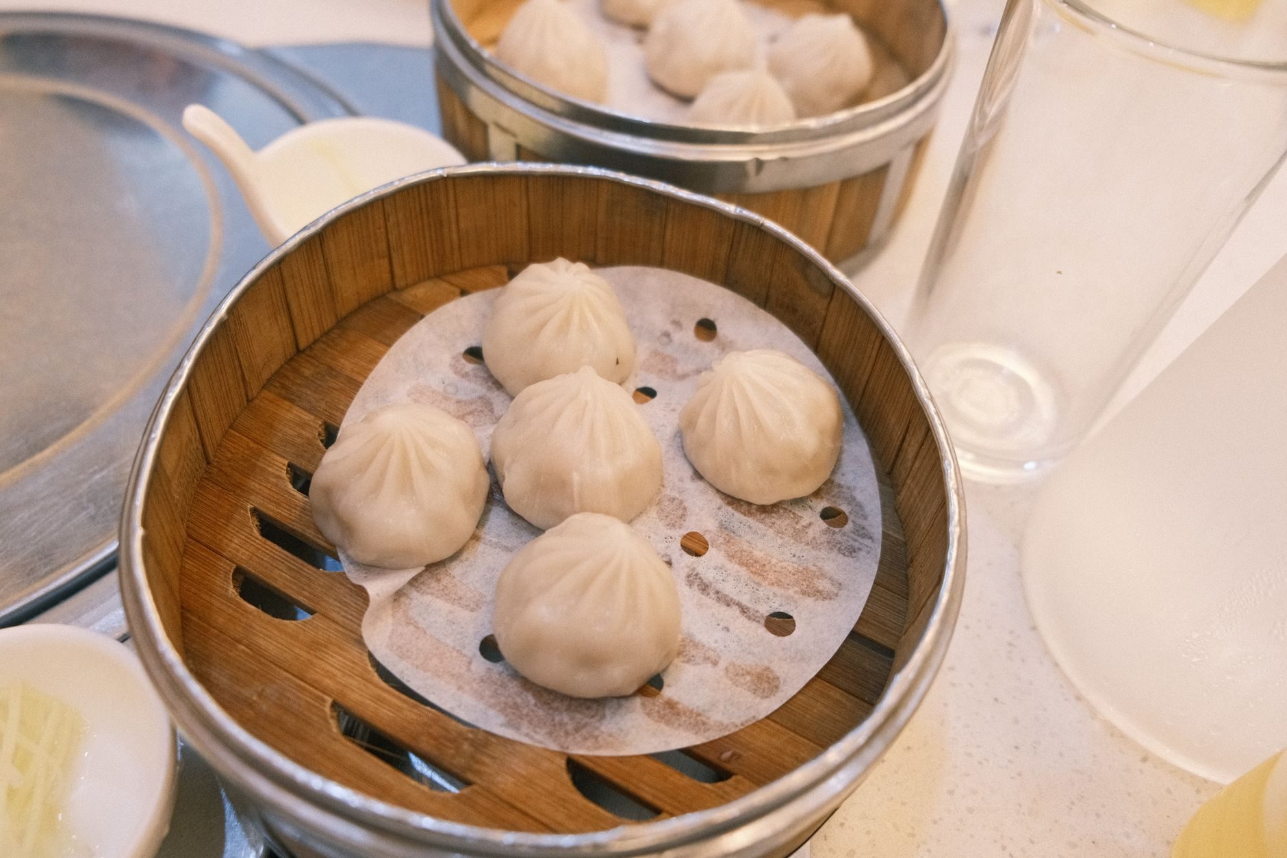 xiaolongbao w bambusowym koszyku, jeden uniesiony pałeczkami