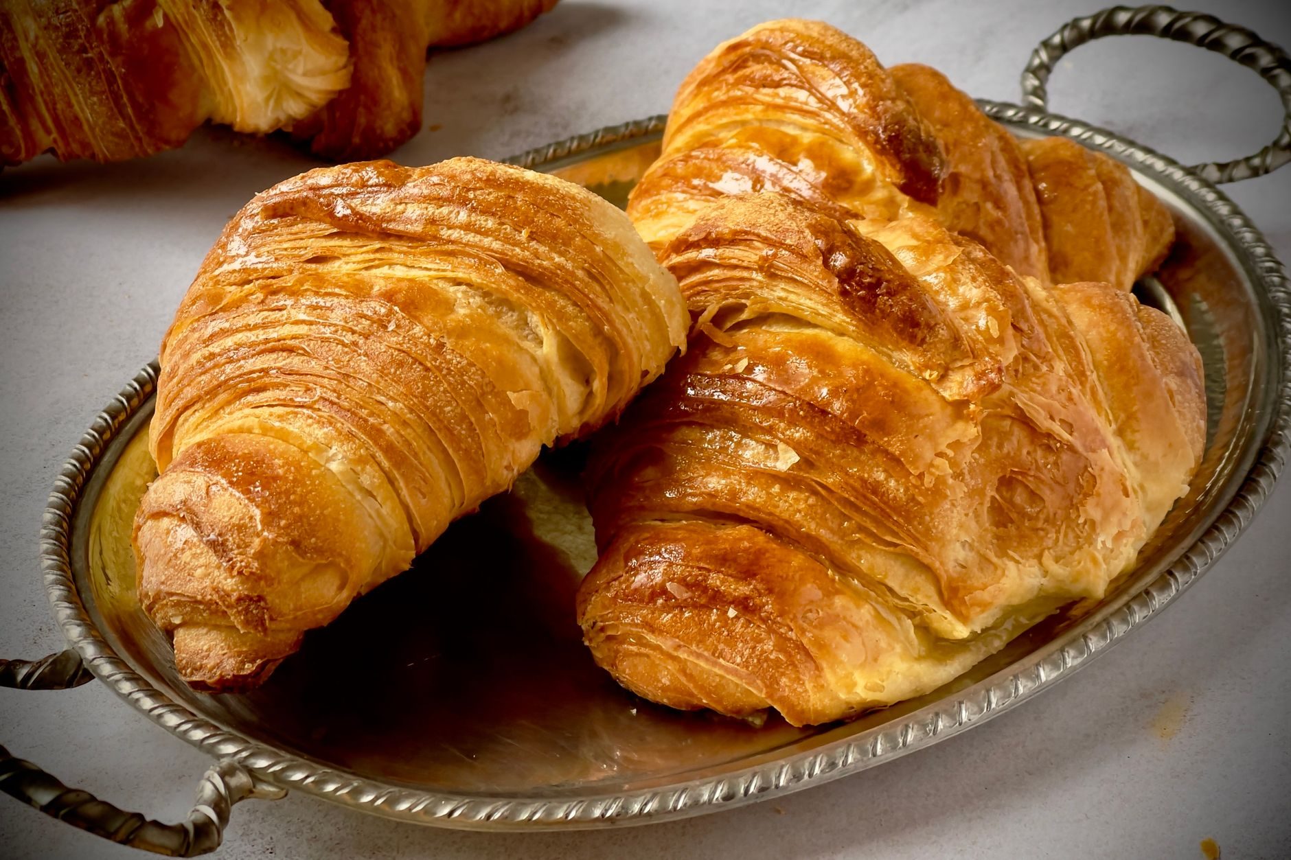 złociste croissanty, jeden przełamany z widocznymi warstwami