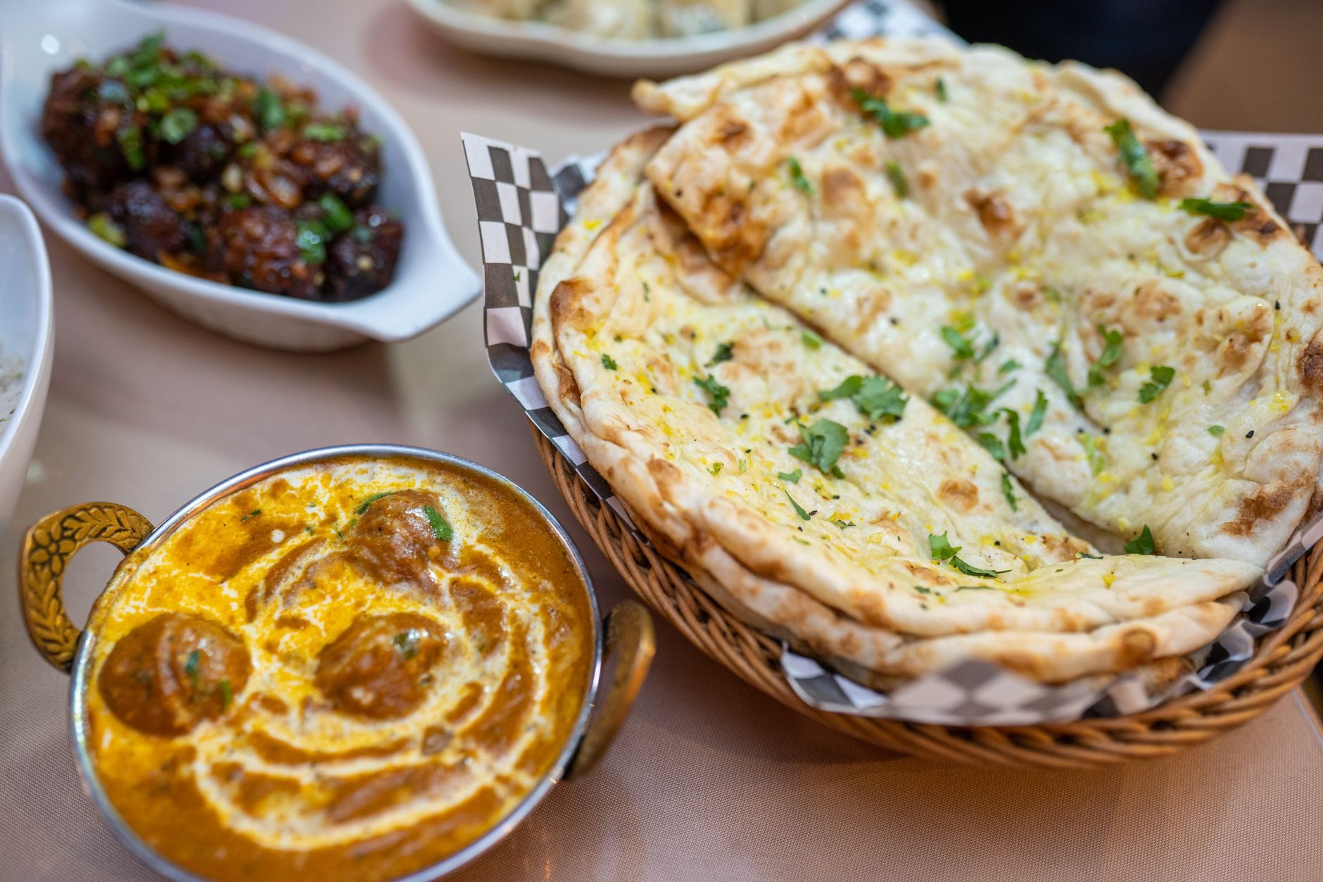 butter chicken w miedzianej miseczce ze śmietanowym zawijasem i naan