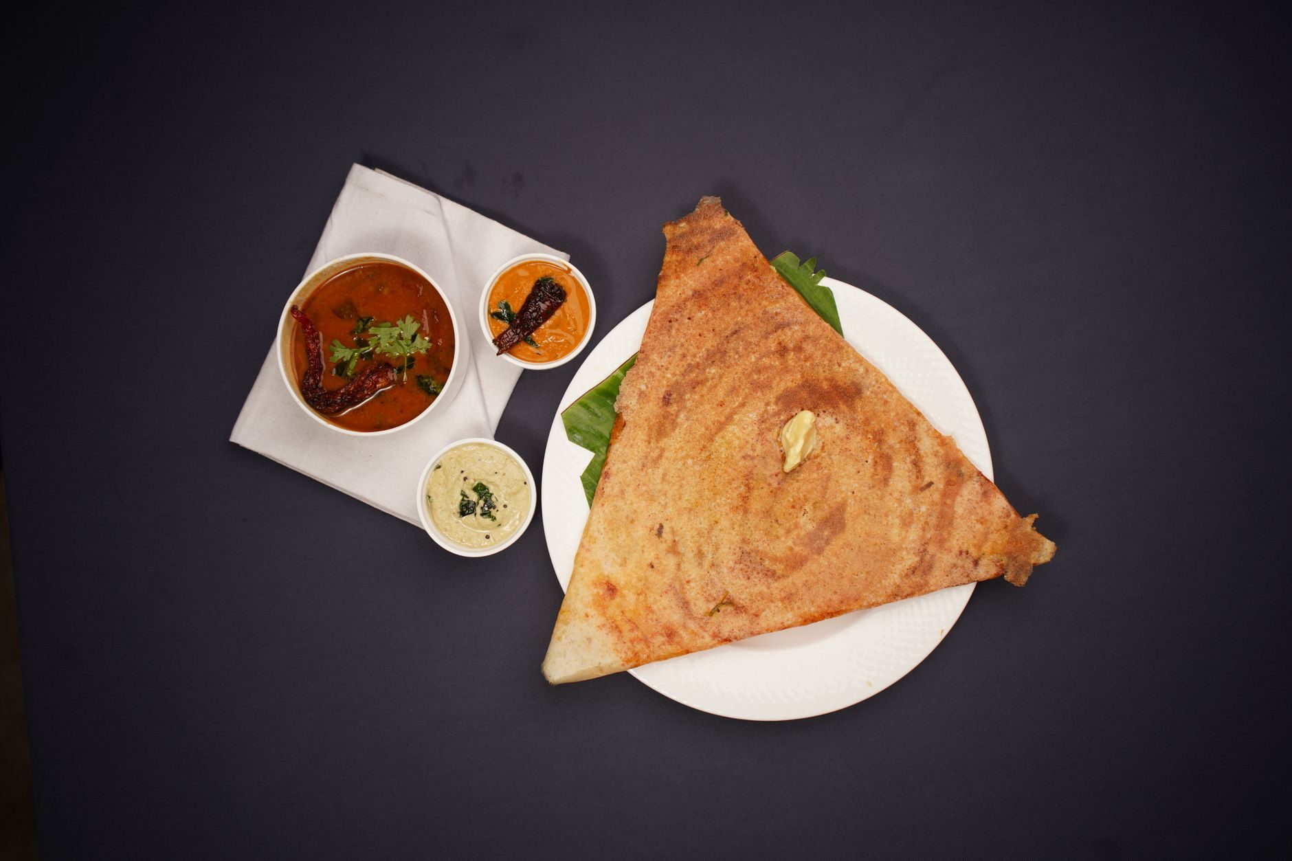 zwinięta w rulon złota dosa z miseczkami sambharu i chutneyu