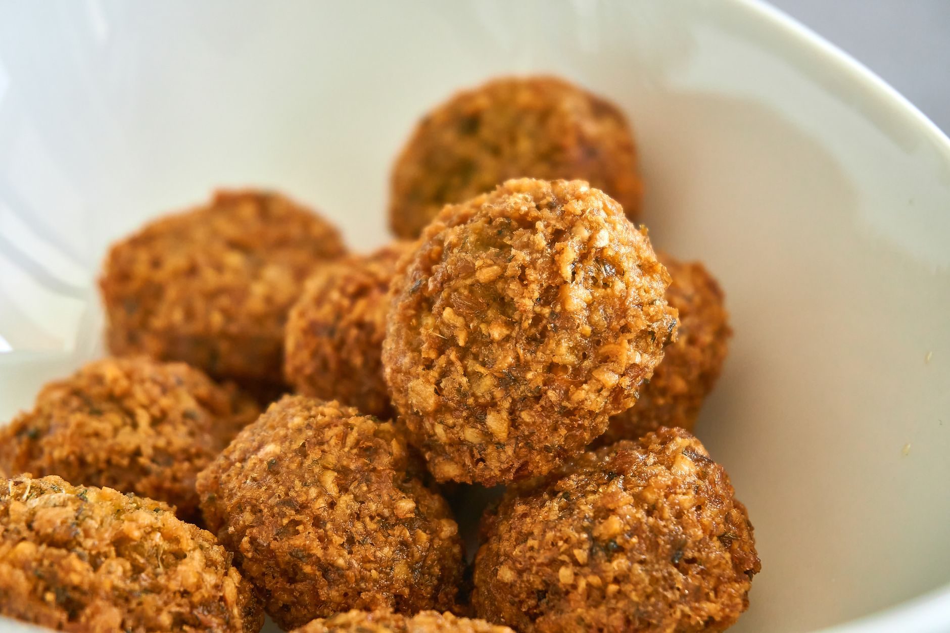 pita wypchana kulkami falafela, sałatką i polana tahiną w papierowej serwetce