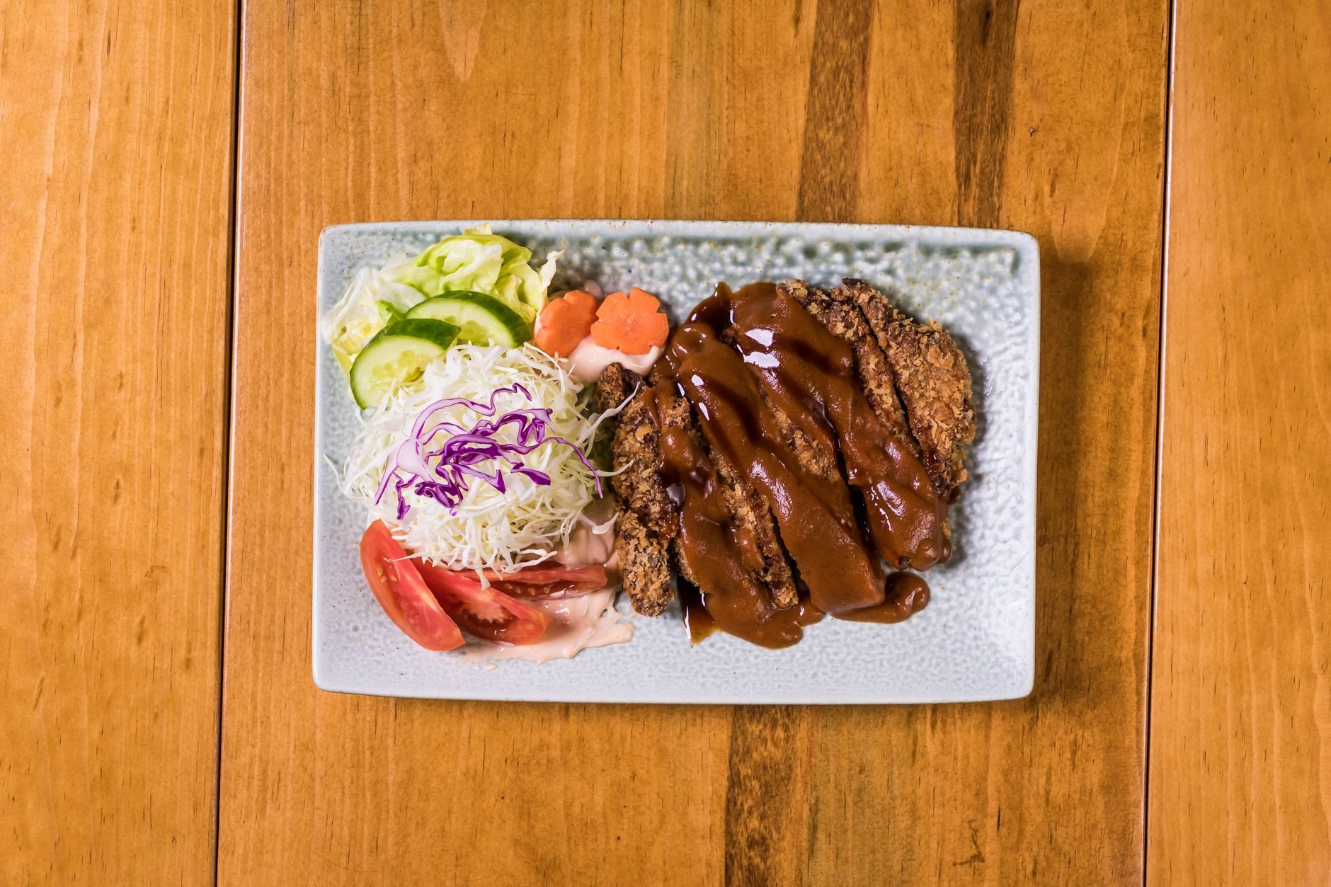 pokrojony kotlet tonkatsu na kapuście z miseczką sosu