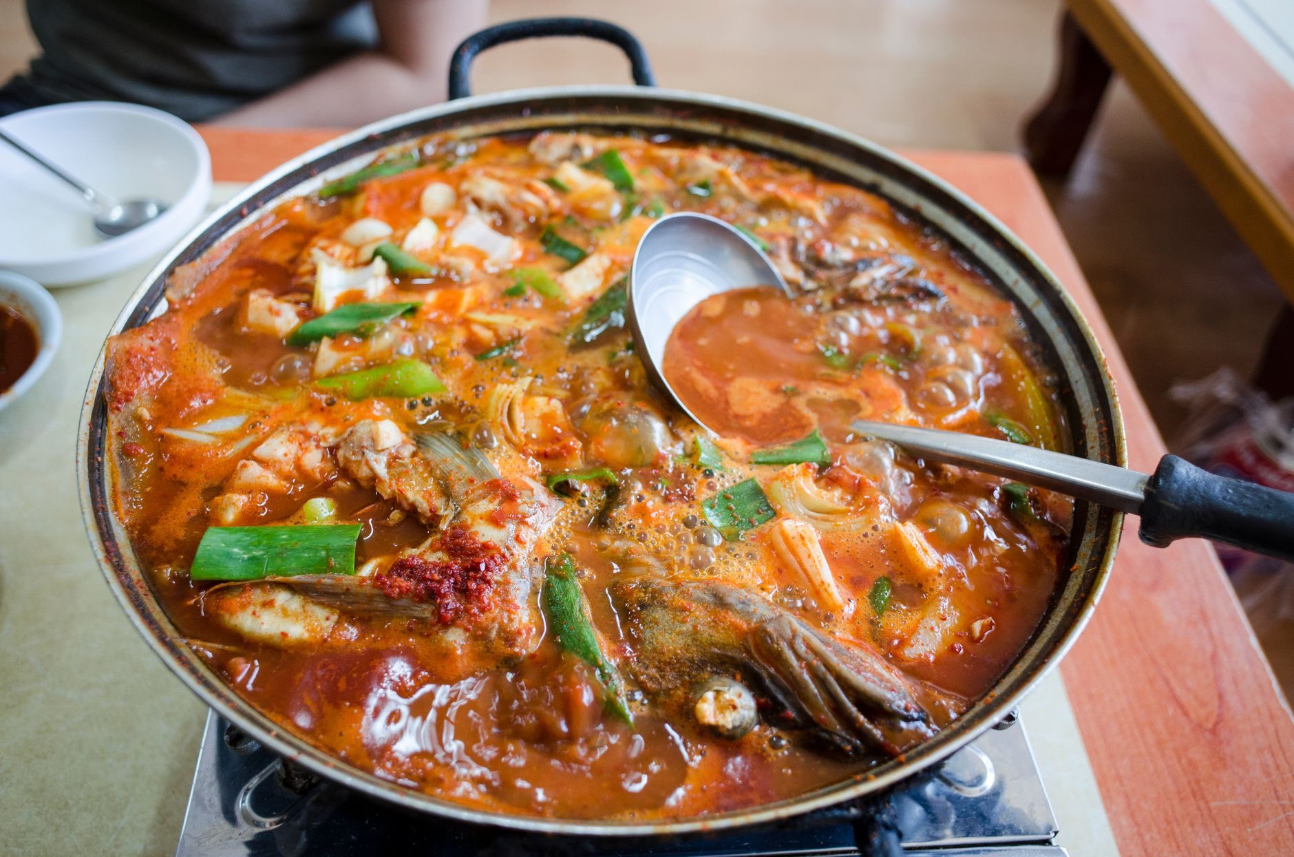 bulgocząca czerwona zupa kimchi w kamiennym garnku z tofu