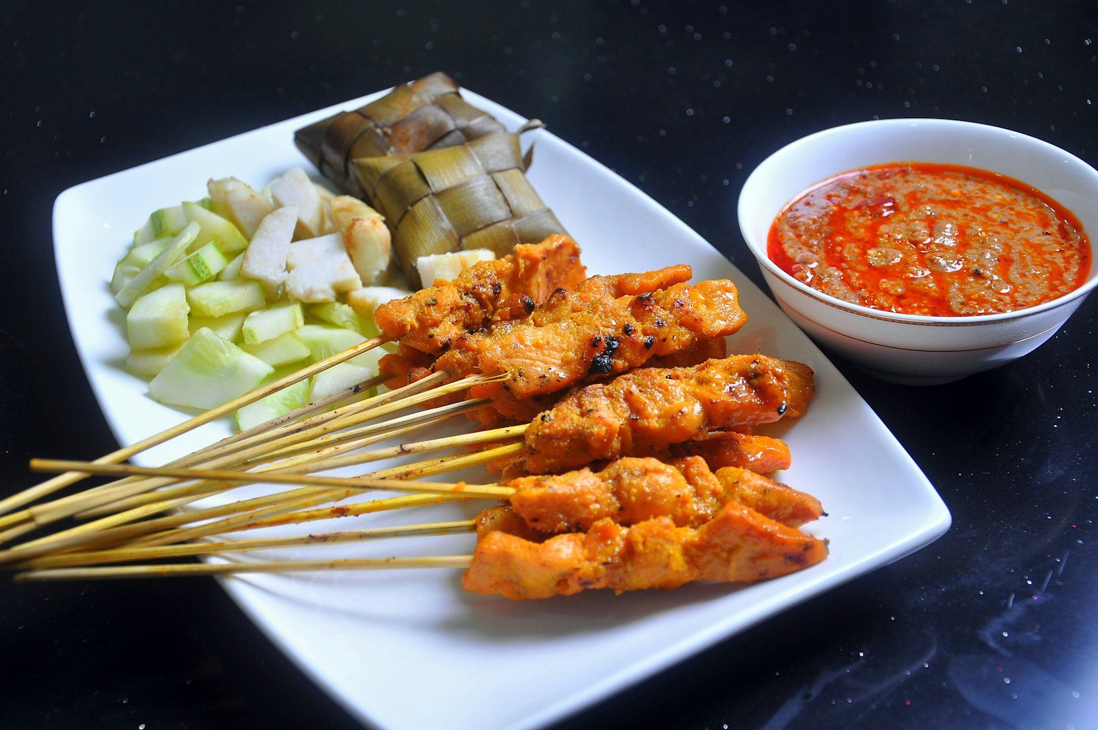 szaszłyki satay opiekane nad żarem węgli, obok miseczka sosu orzechowego