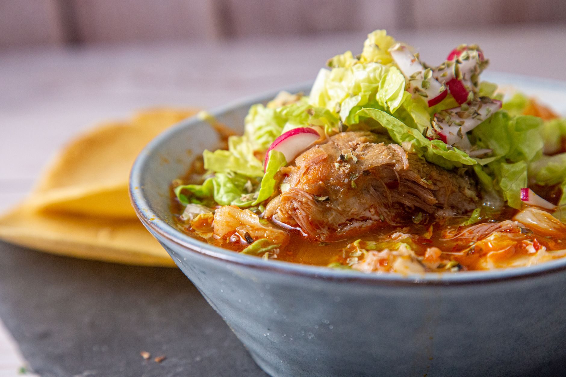 Miska pozole rojo z dodatkami: kapusta, rzodkiewka, oregano