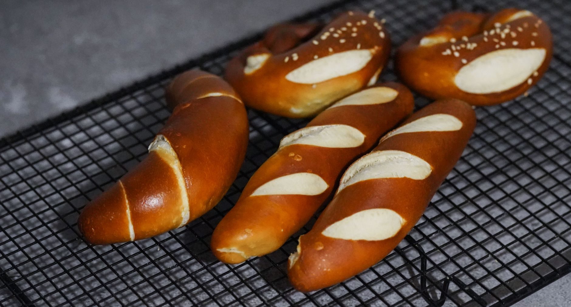 stos ciemnozłotych precli z grubą solą na drewnianym kołku