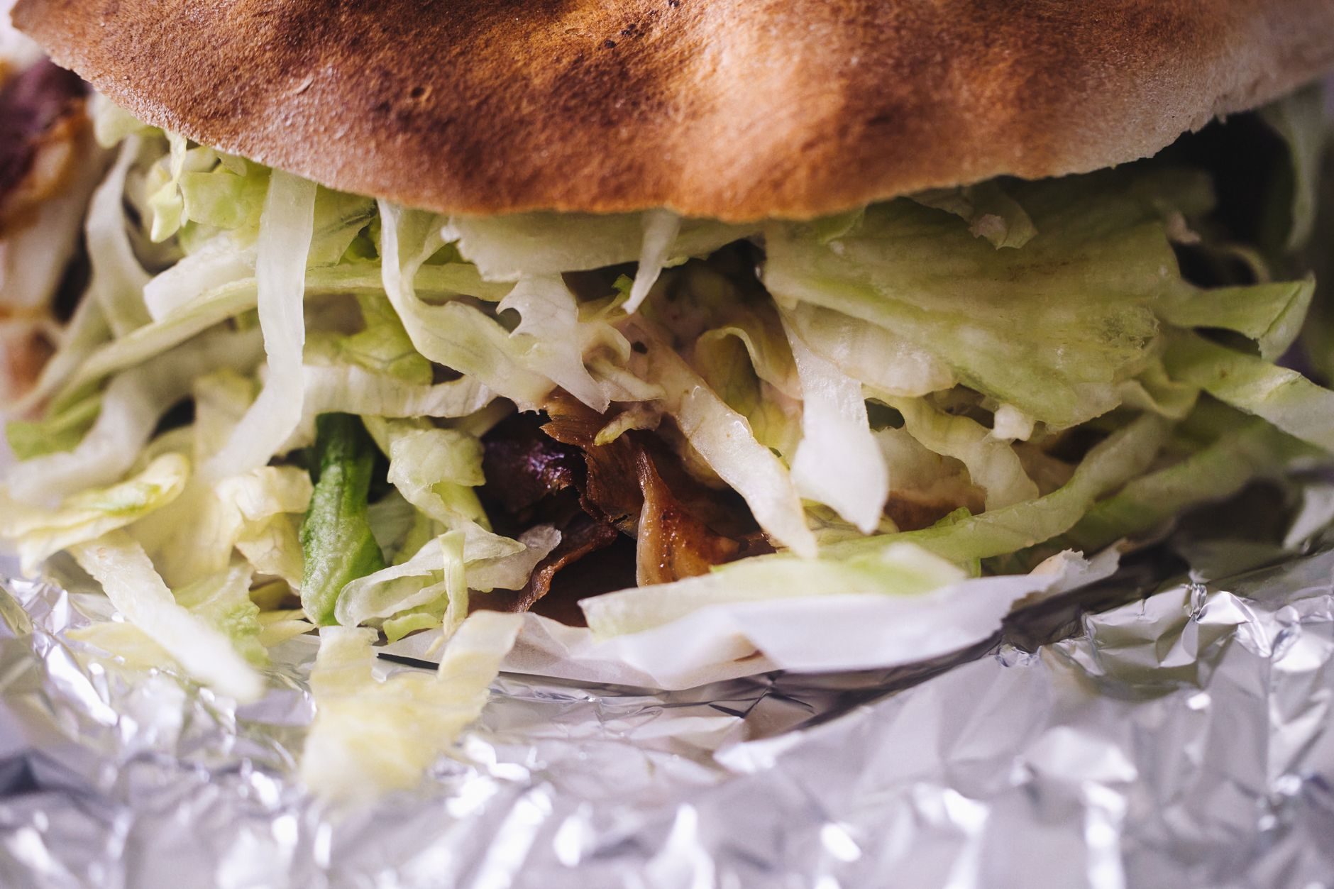 przepełniona bułka döner z mięsem i surówkami w papierze