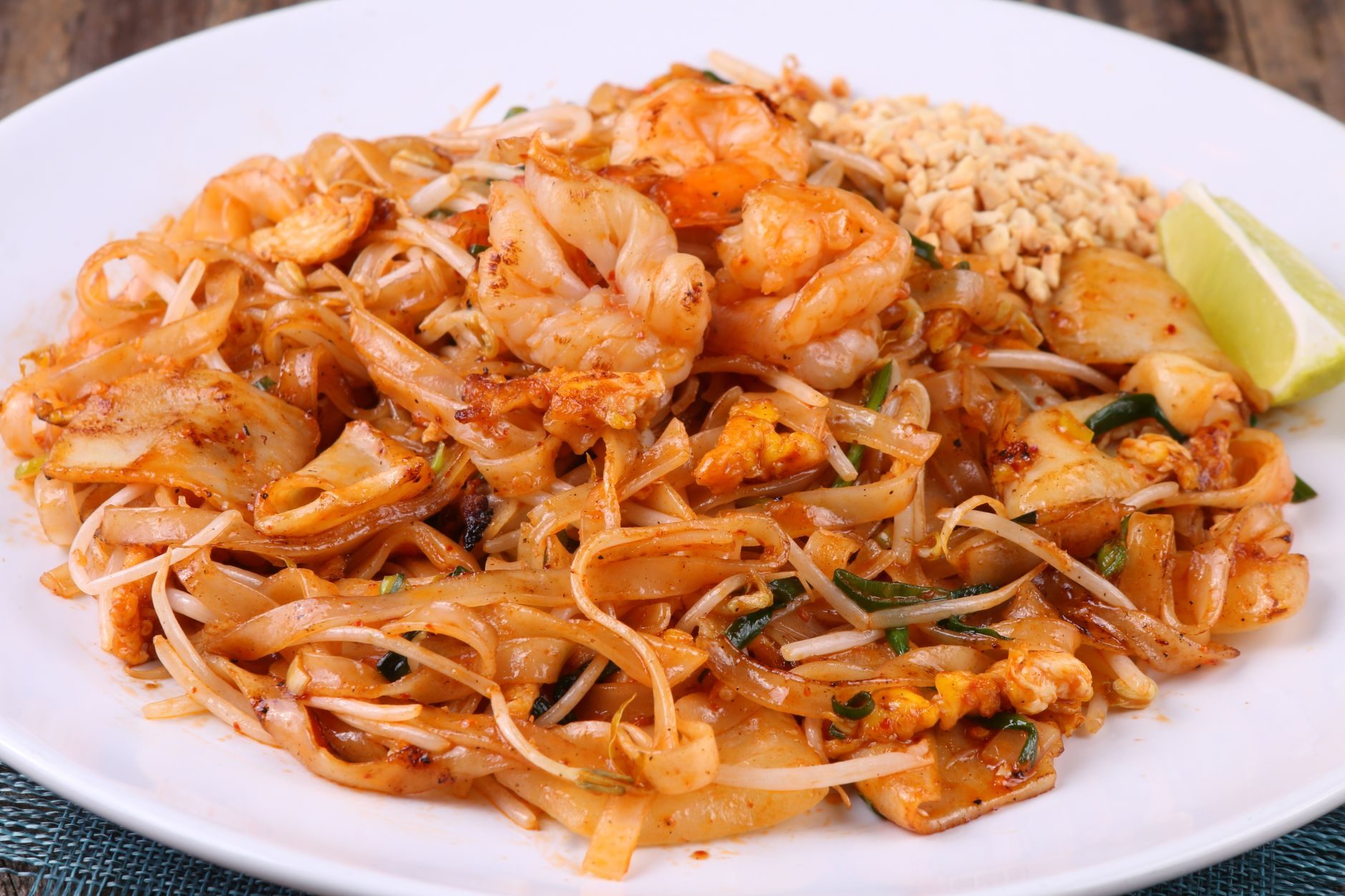 pad thai z krewetkami, limonką i orzeszkami na talerzu