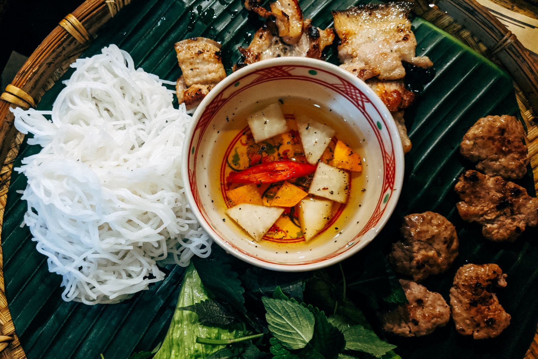 miseczka bun cha z grillowanym mięsem w sosie, makaron i zioła obok